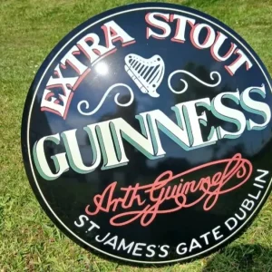 Round vintage Guinness Extra Stout enamel sign with harp logo and Arthur Guinness signature – ideal for collectors or pub walls.
