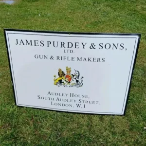 Vintage James Purdey & Sons enamel sign with coat of arms and London address – collectible gunmaker signage.